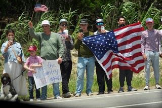 People watch as President Donald Trump and first lady Melania Trump pass in a motorcade in Kerrville, Texas